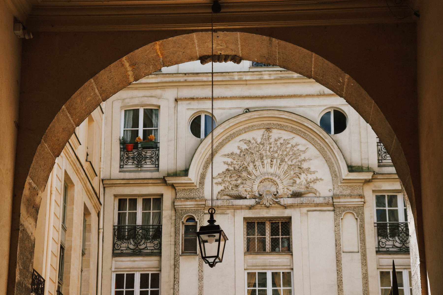 A stone archway framing a classical Parisian courtyard façade
